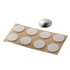 White circular stickers on a brown paper backing with a metal disc above them on a white background