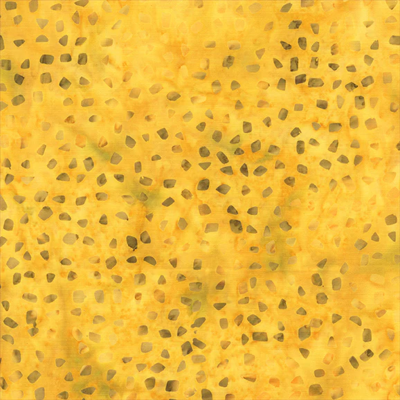 Yellow batik fabric with a scattered pattern of small green speckles.
