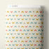 A roll of Cloud9 fabric with a repeating pattern of colorful dragonflies on a warm cream background, shown against a neutral light beige wall.