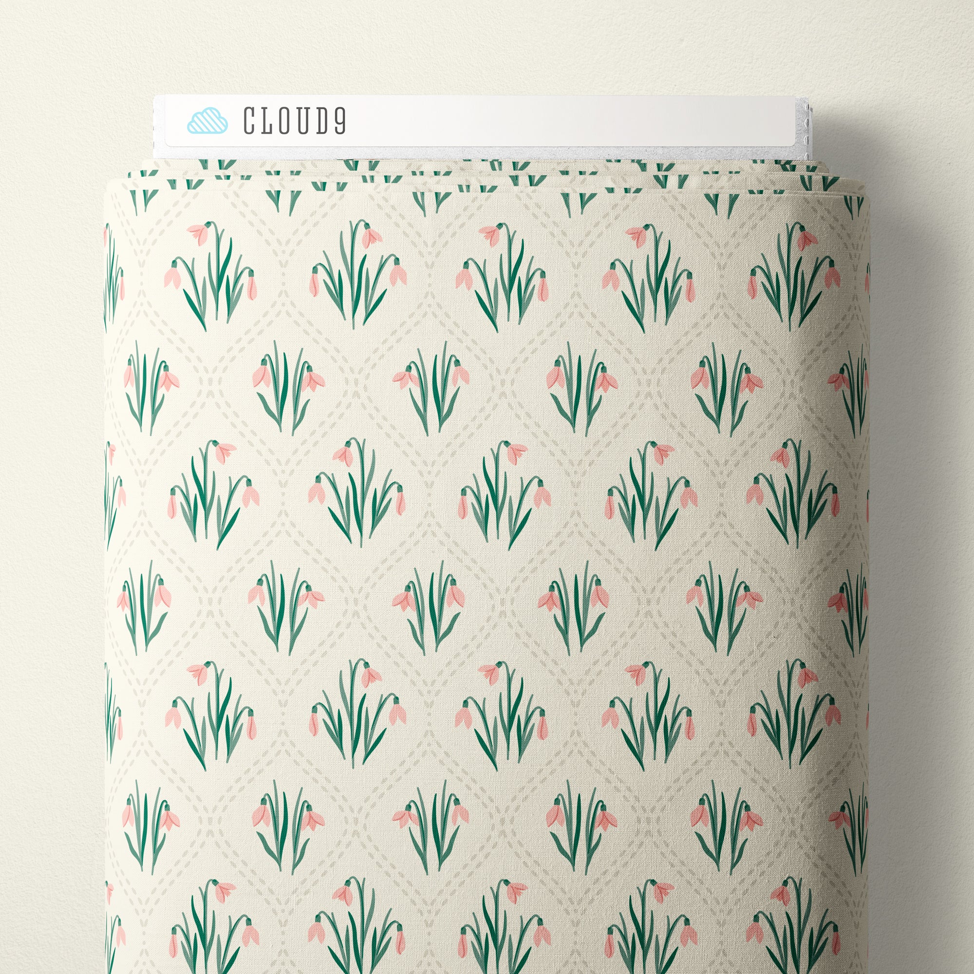A roll of fabric with a repeating pattern of pink tulips and green leaves on a cream background, with a white header card labeled CLOUD9 at the top.