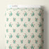 A roll of fabric with a repeating pattern of pink tulips and green leaves on a cream background, with a white header card labeled CLOUD9 at the top.