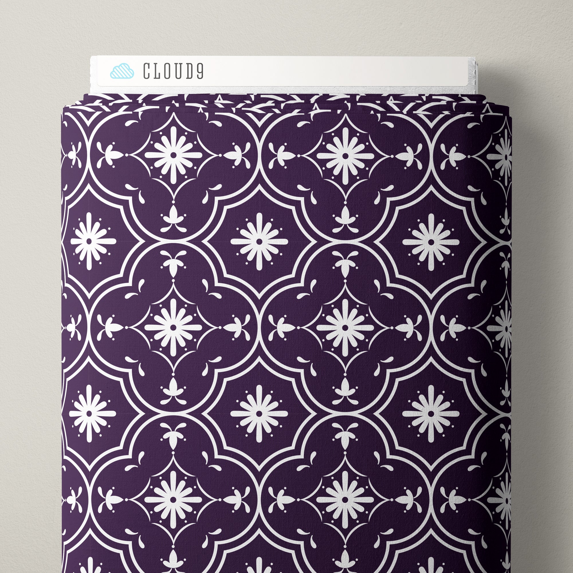 A roll of patterned fabric with a dark purple and white geometric floral design, shown standing upright with a white label that reads CLOUD9 at the top.
