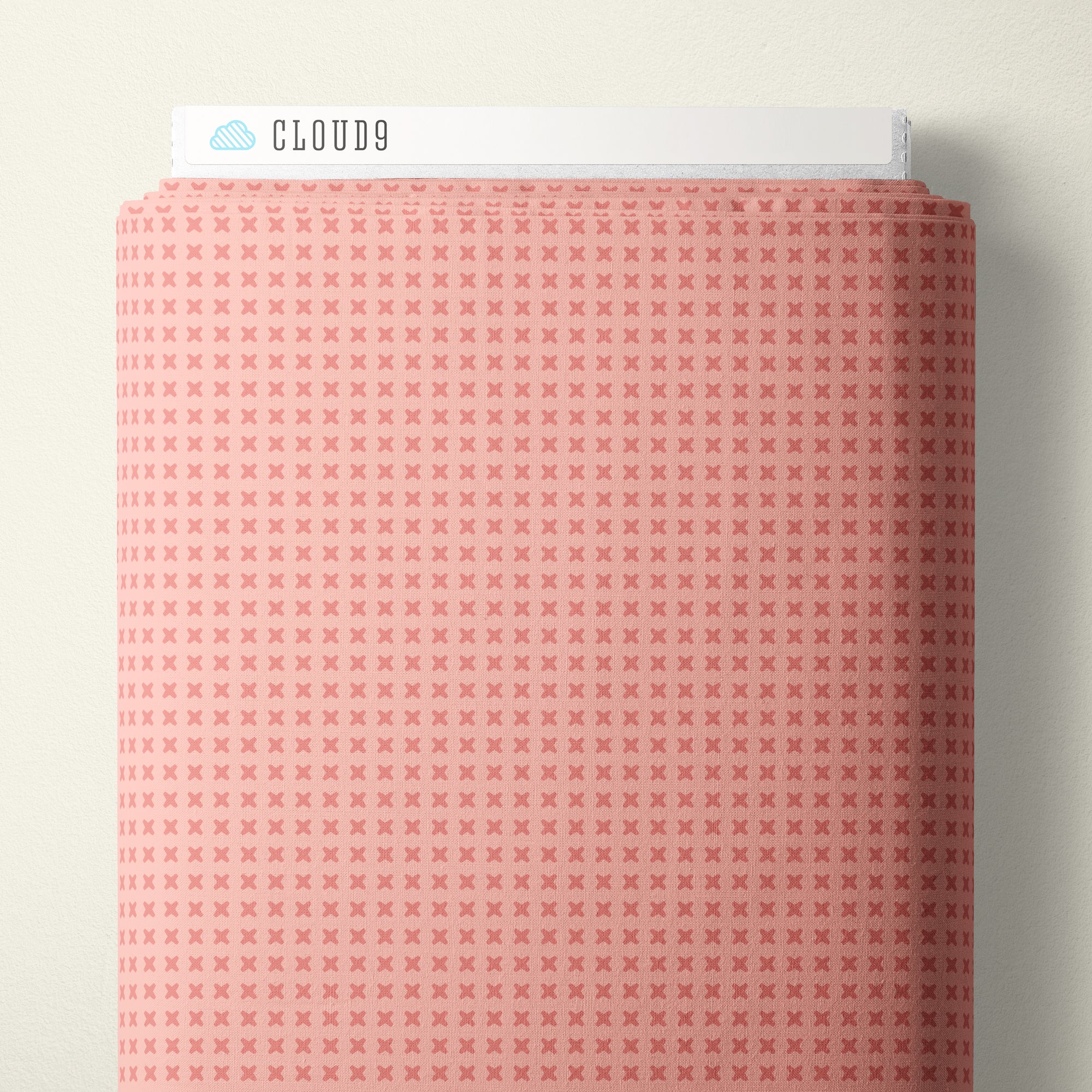 A close-up of a pink fabric with a repeating small cross pattern, shown with a white header card labeled CLOUD9 at the top against a light neutral background.