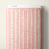 Cloud9 branded fabric bolt with a vertical birch tree pattern in pink and off-white, photographed against a neutral light beige wall.