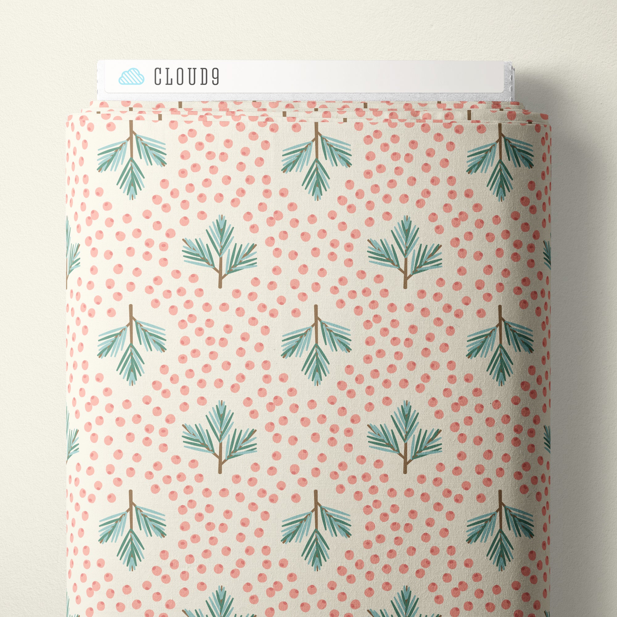 A roll of fabric with a repeating pattern of green pine branches on a cream background with small coral-pink dots, with a white header card reading CLOUD9 at the top.