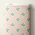 A roll of fabric with a repeating pattern of green pine branches on a cream background with small coral-pink dots, with a white header card reading CLOUD9 at the top.