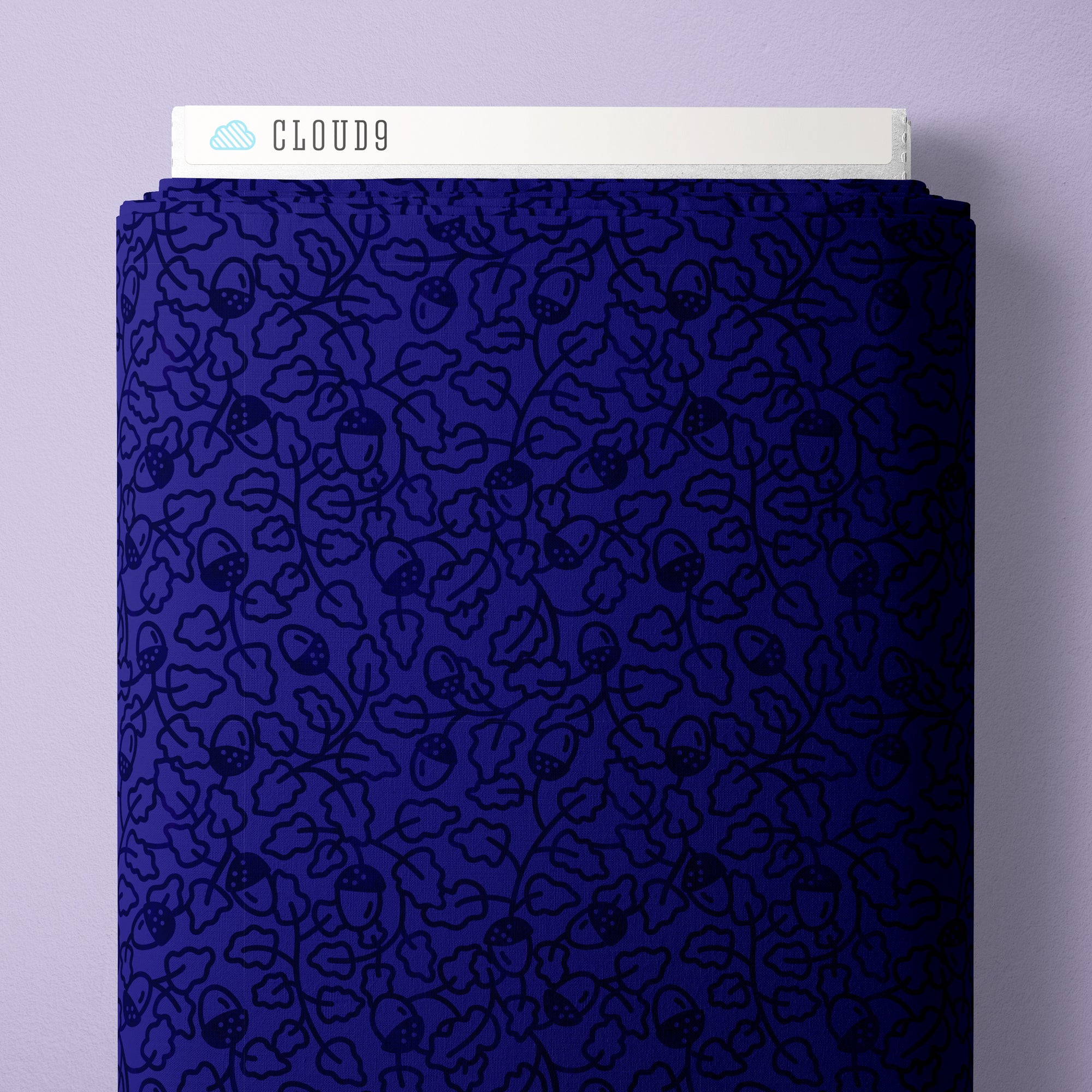 A close-up of a dark blue fabric bolt with an all-over black floral and acorn line pattern, shown standing against a light lavender background. The white top border has the text 'CLOUD9' with a small cloud icon.