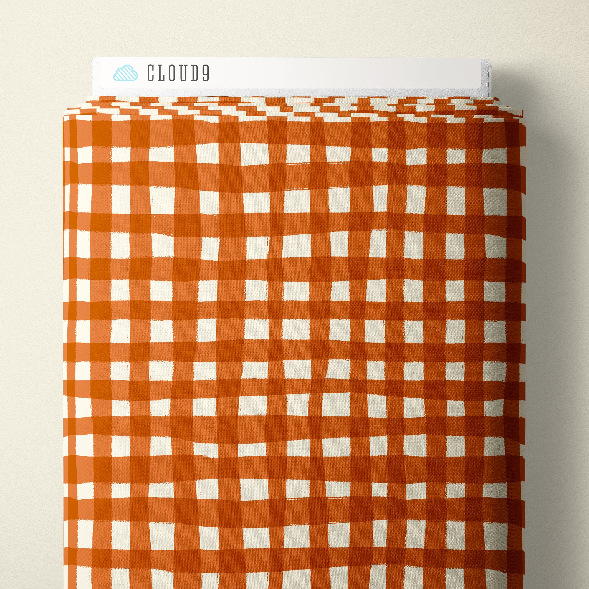 A roll of fabric or paper with an orange and white hand-drawn checkered pattern, shown with a white header card labeled CLOUD9 on a light beige background.