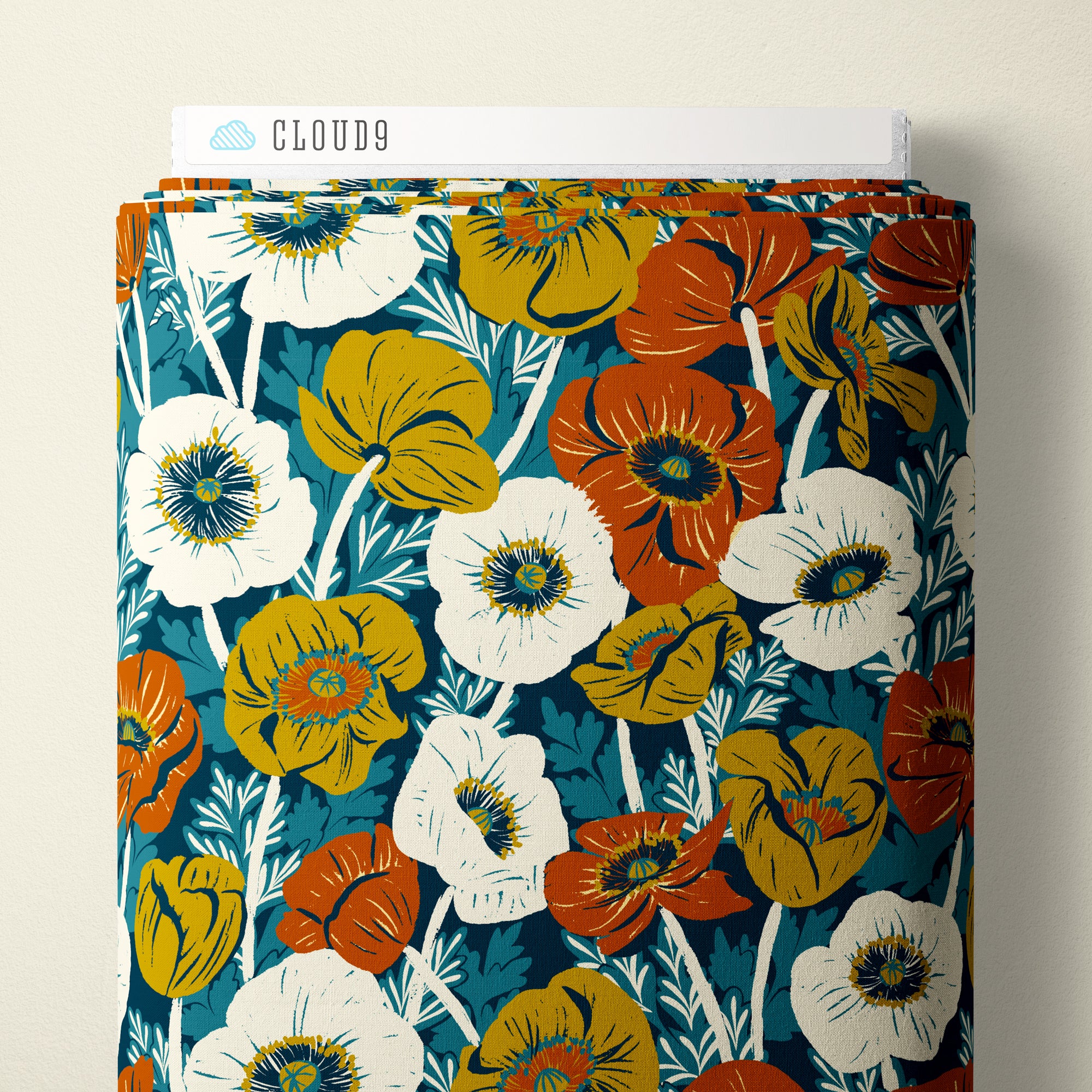 A folded bolt of patterned fabric with a floral print, displayed against a light beige wall. The top edge shows a white paper label with the brand name 'CLOUD9'.