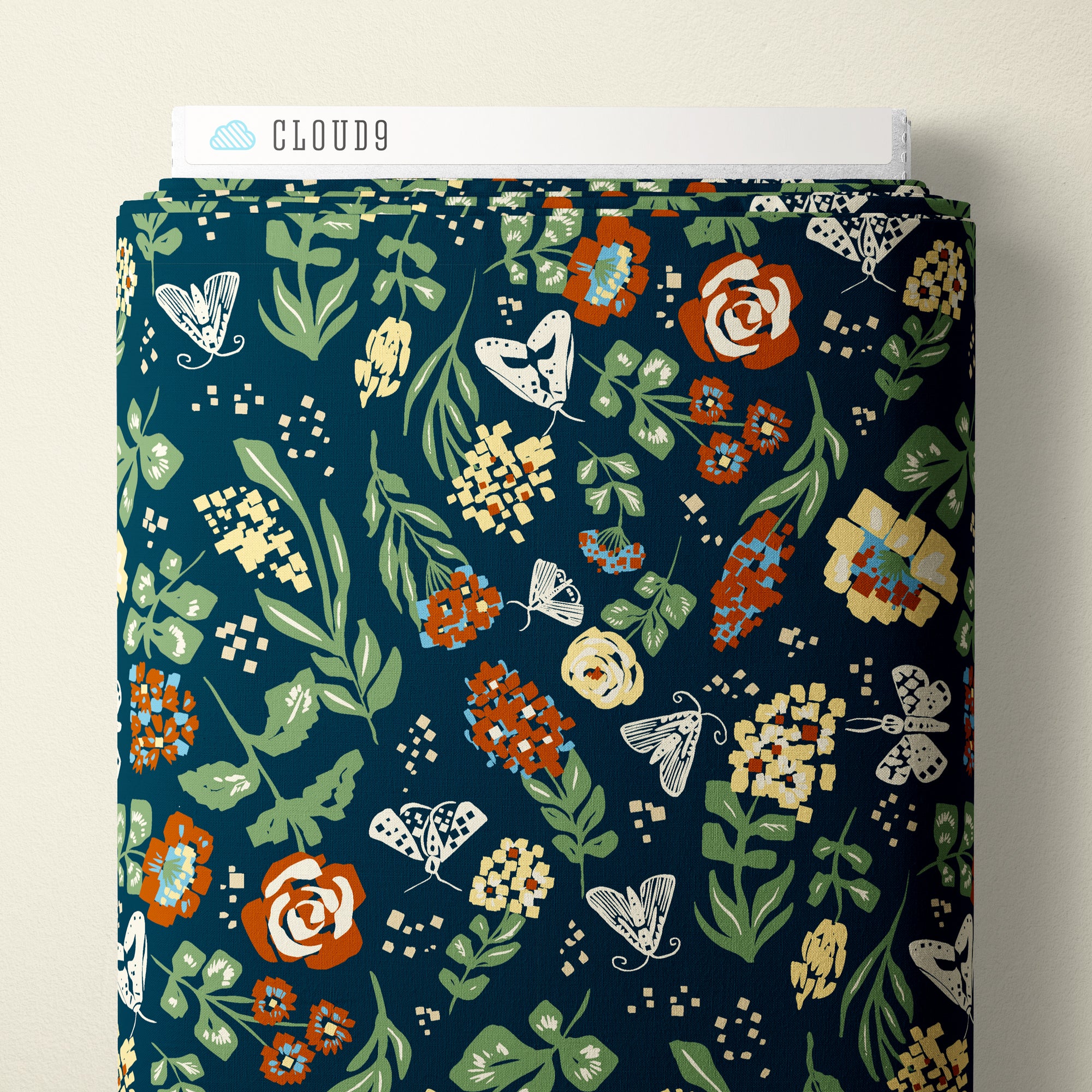 A roll of fabric with a dark teal blue background and a detailed botanical pattern featuring green leaves, orange and cream flowers, and white butterflies. A white cardboard header at the top reads CLOUD9.