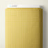 A roll of patterned fabric with a repeating small white x motif on a warm yellow background, shown against a light neutral wall. A white header card at the top reads CLOUD9.