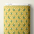 A roll of fabric with a repeating pattern of white snowdrops on a mustard yellow background, featuring green stems and leaves and a white dotted diamond lattice. A white label at the top of the roll is printed with the brand name 'CLOUD9'.