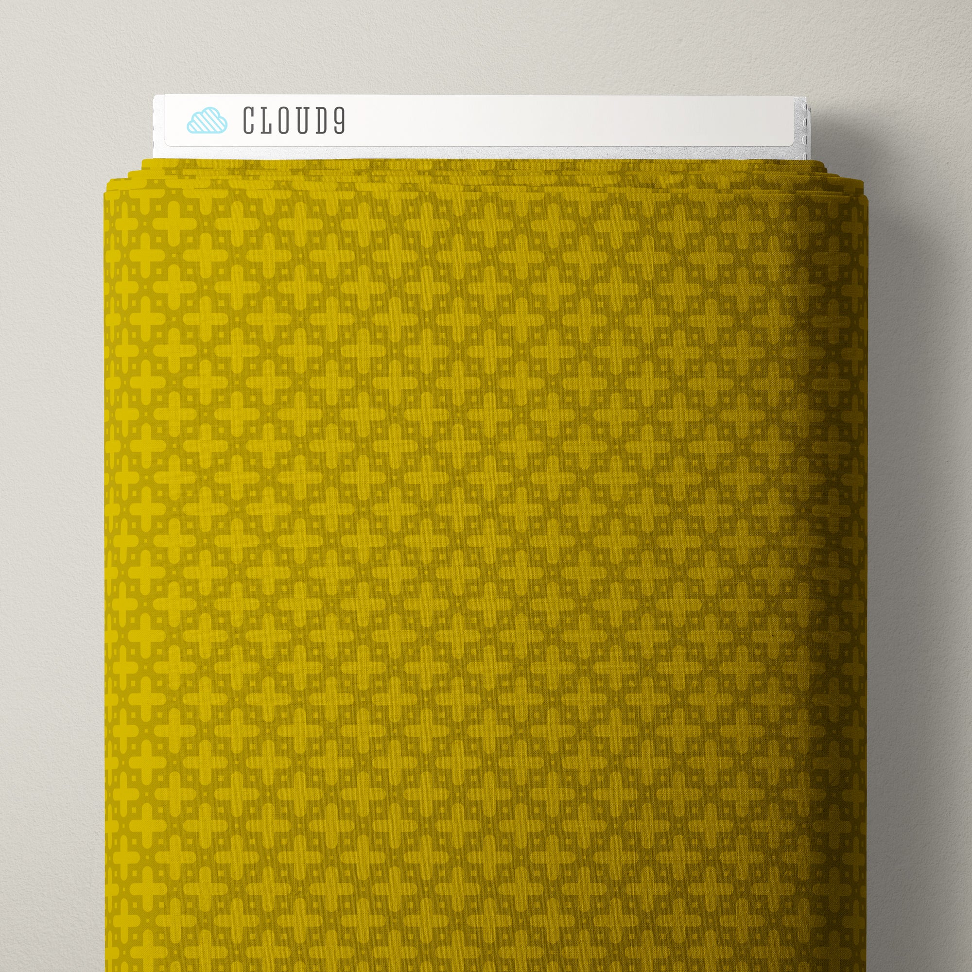 A close-up of a yellow fabric swatch with a repeating geometric pattern, with a white label reading CLOUD9 visible at the top against a light gray background.