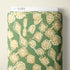 A roll of fabric with a green background and a beige and cream abstract geometric pattern, shown with a white header card labeled CLOUD9.