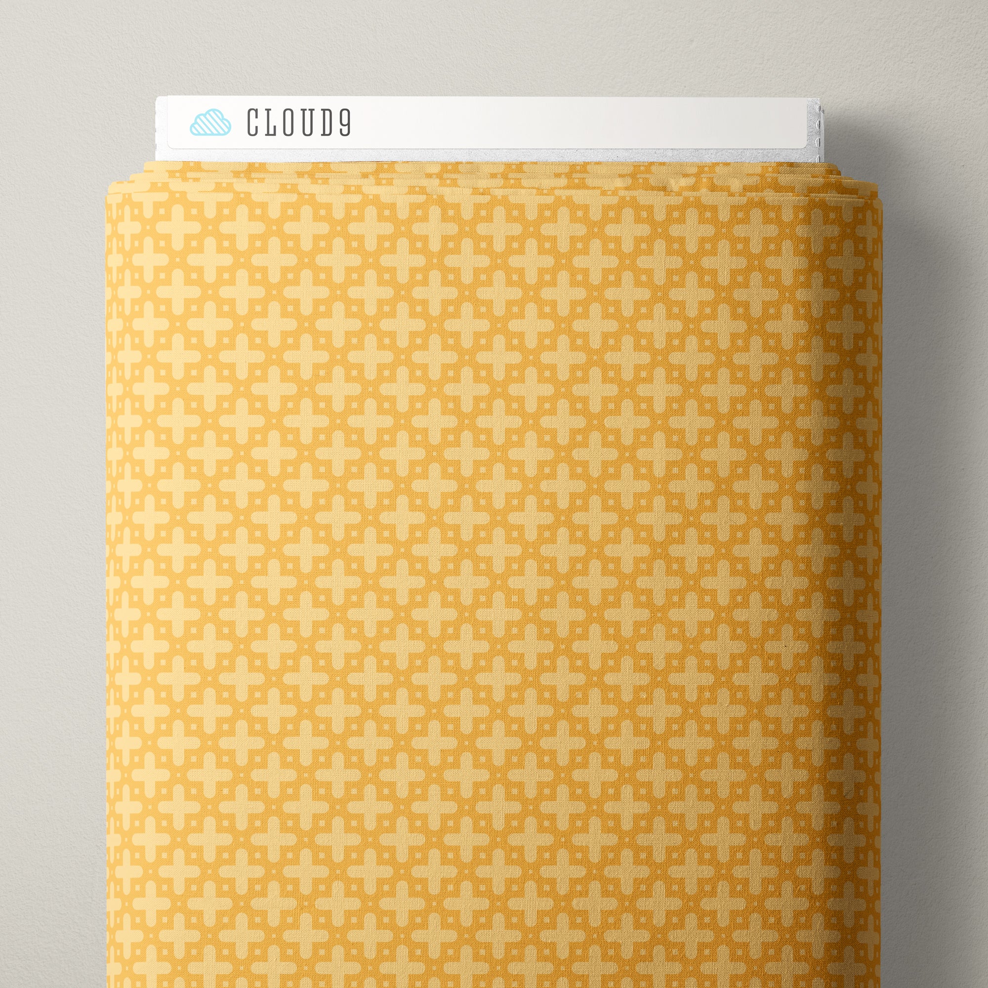 A roll of patterned fabric with a repeating geometric lattice design in mustard yellow and cream, shown with a white header card labeled CLOUD9.