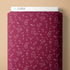 Maroon fabric with white symbols on a beige background