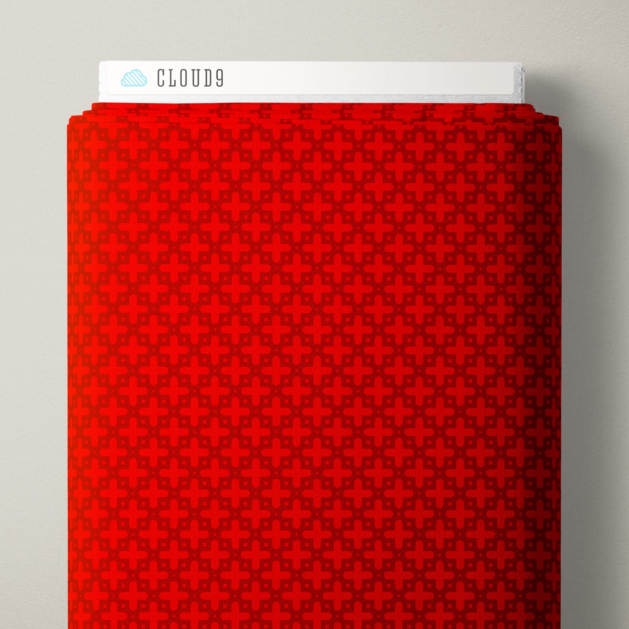 A folded red fabric with a repeating dark geometric pattern, shown against a light gray background. A white label at the top reads CLOUD9 with a small blue cloud icon.