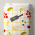 A roll of Cloud9 brand fabric featuring a white background with a light pink and yellow plaid grid pattern, decorated with illustrations of a purple wine bottle, red tomatoes, yellow olives, bread, cheese, and a glass of red wine.