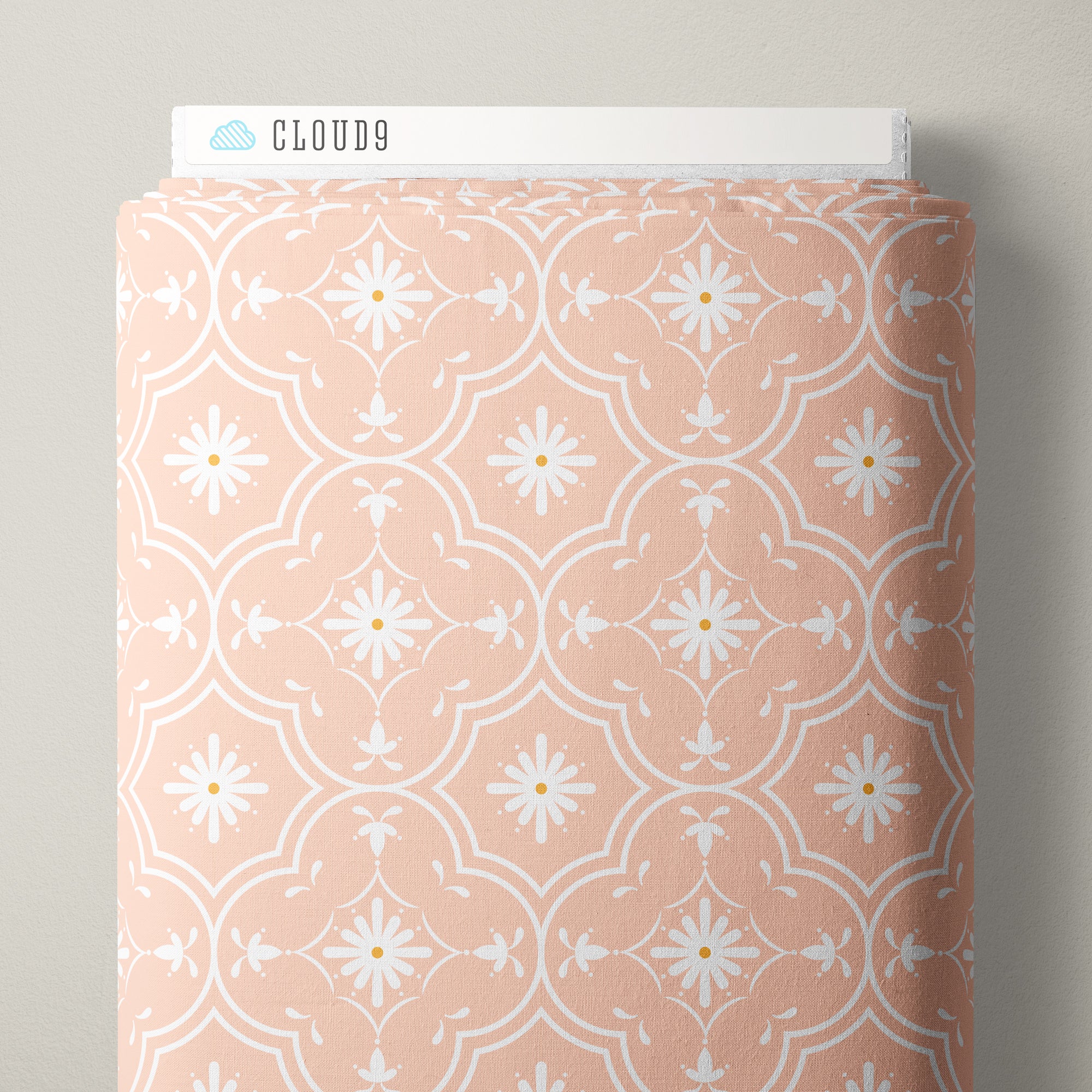 A roll of Cloud9 patterned fabric in a dusty peach-pink color with a white geometric and floral design, shown against a neutral gray background.