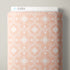 A roll of Cloud9 patterned fabric in a dusty peach-pink color with a white geometric and floral design, shown against a neutral gray background.