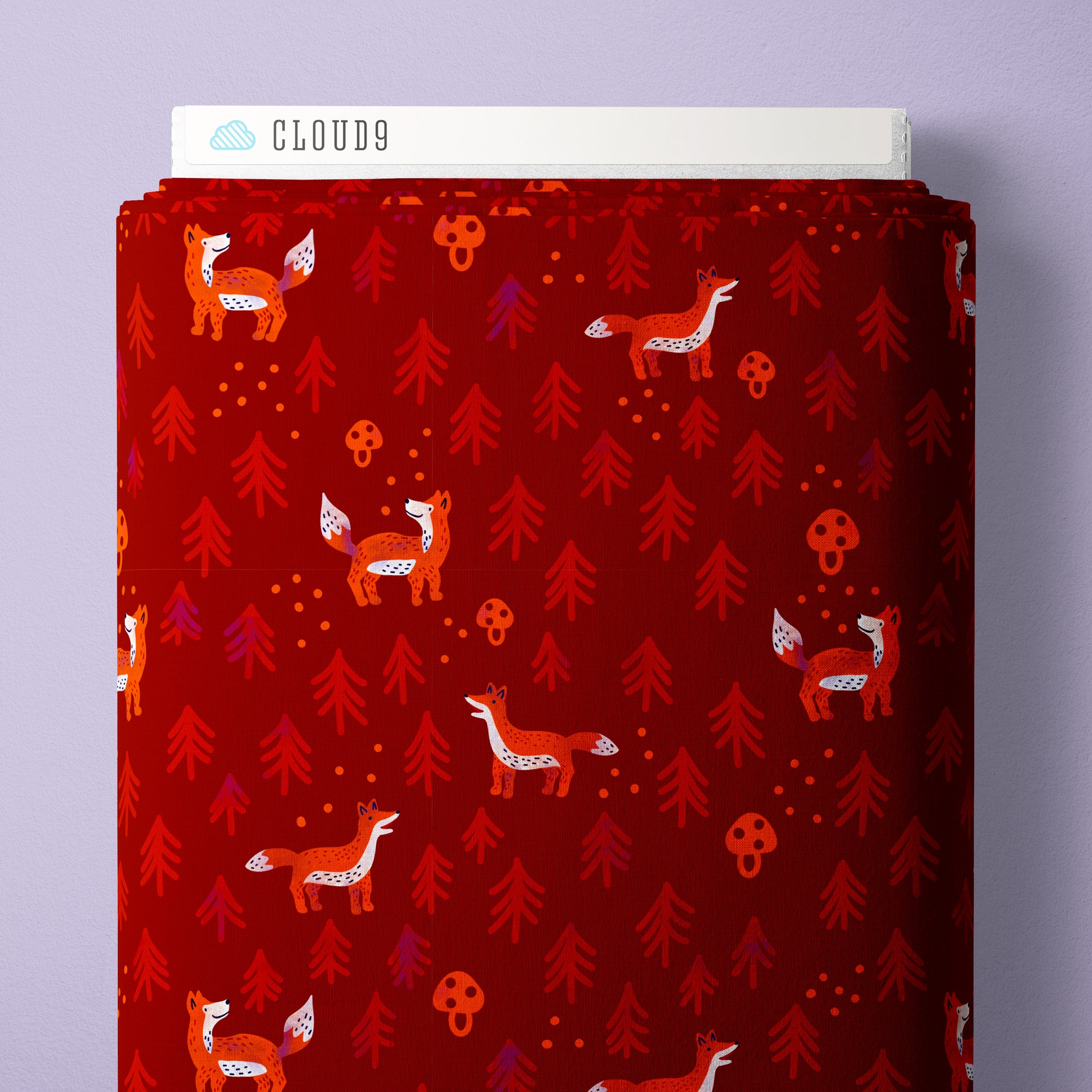 A roll of fabric with a festive red background, featuring a repeating pattern of orange foxes, red pine trees, and small orange mushrooms. The brand name 'CLOUD9' is visible on the white paper header at the top of the roll.