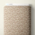 A roll of Cloud9 brand fabric featuring a repeating pattern of small white mushrooms on a warm brown background, shown against a neutral off-white wall.
