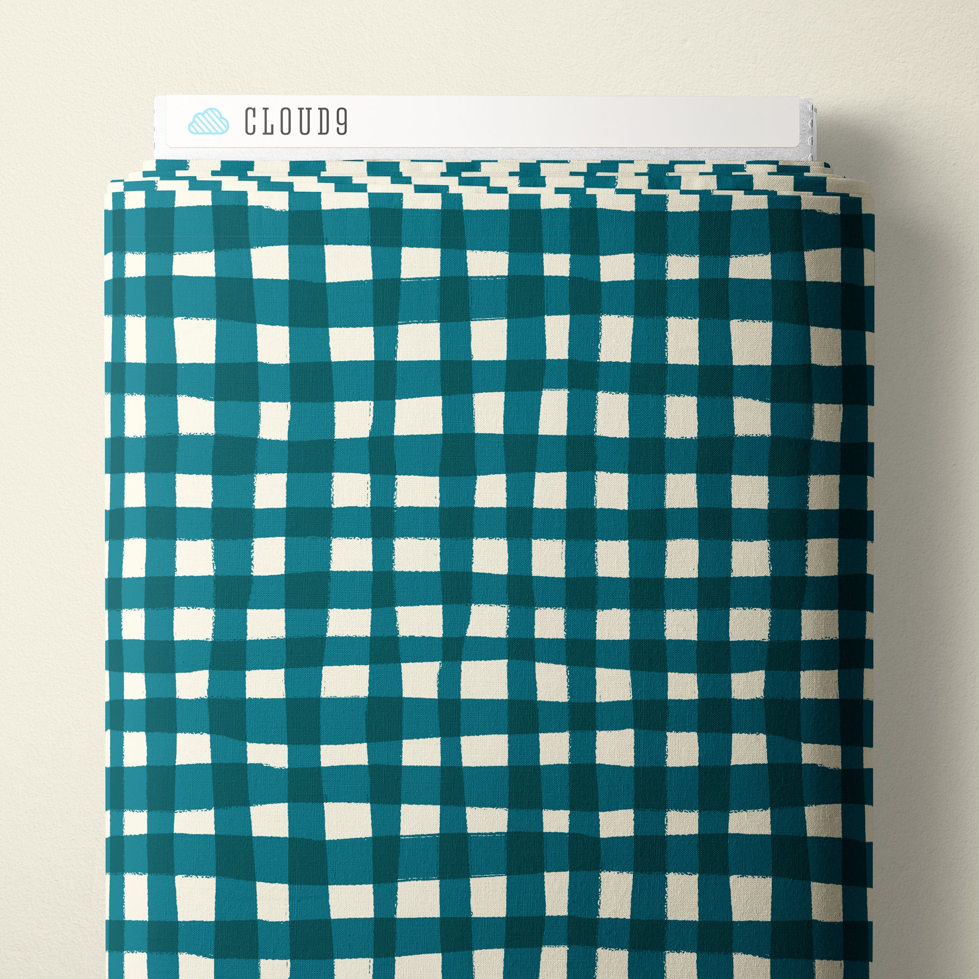 A folded piece of fabric with a teal and white gingham check pattern, displayed against a light beige background with a white paper label reading CLOUD9 at the top.