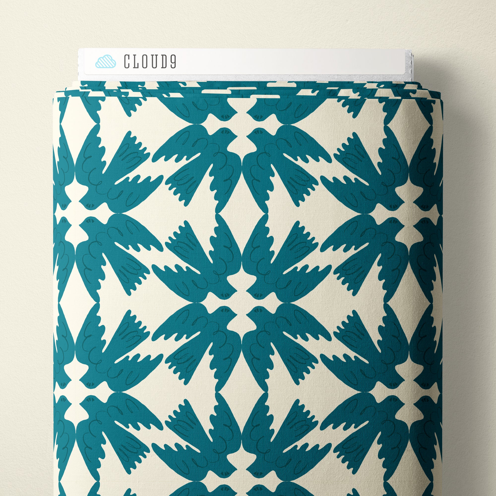 A roll of wallpaper with a repeating teal bird pattern on an off-white background, with a white header card labeled CLOUD9 visible at the top, set against a neutral beige wall.