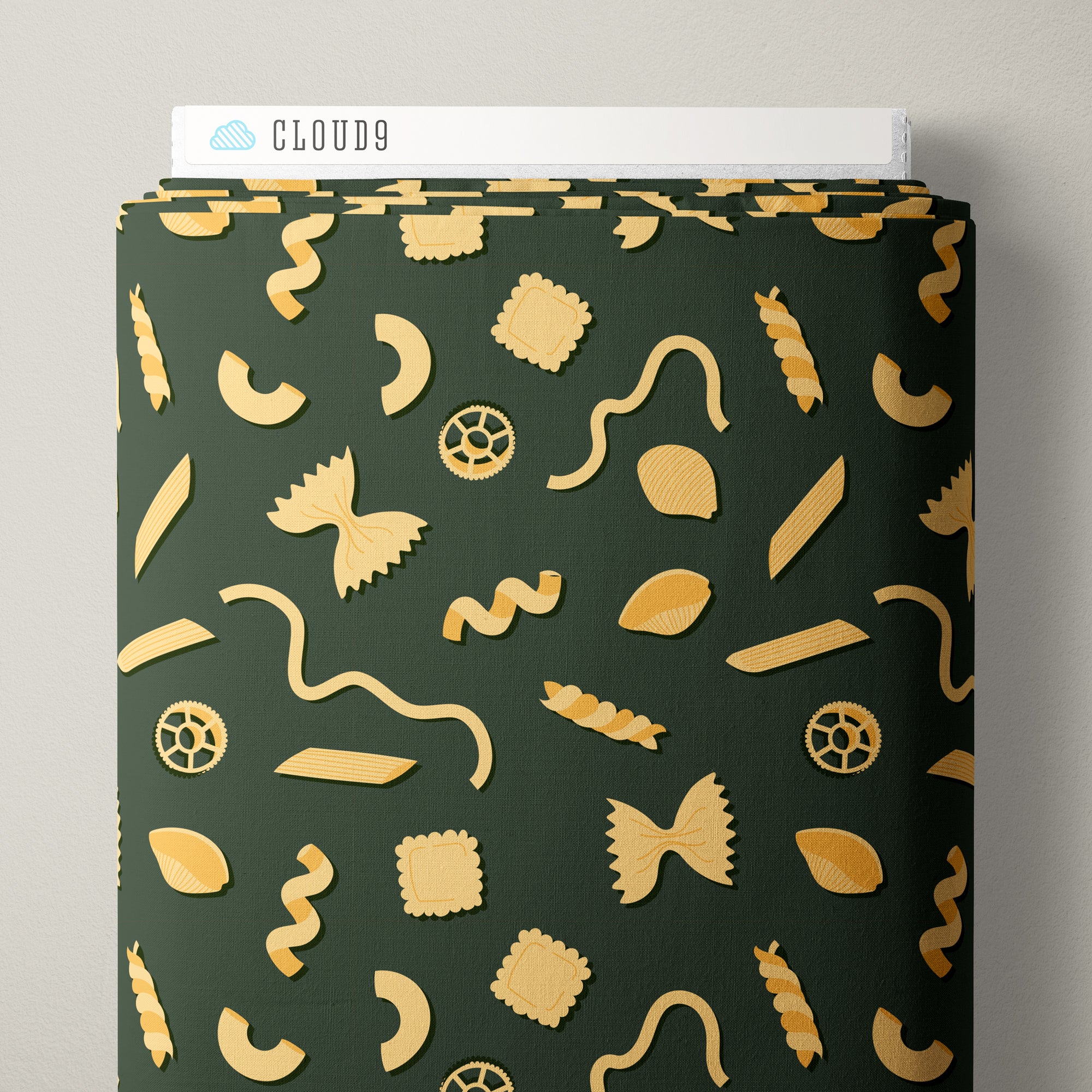A roll of dark green fabric with a repeating pattern of gold pasta shapes, shown partially unrolled with a white Cloud9 box visible at the top against a light gray background.