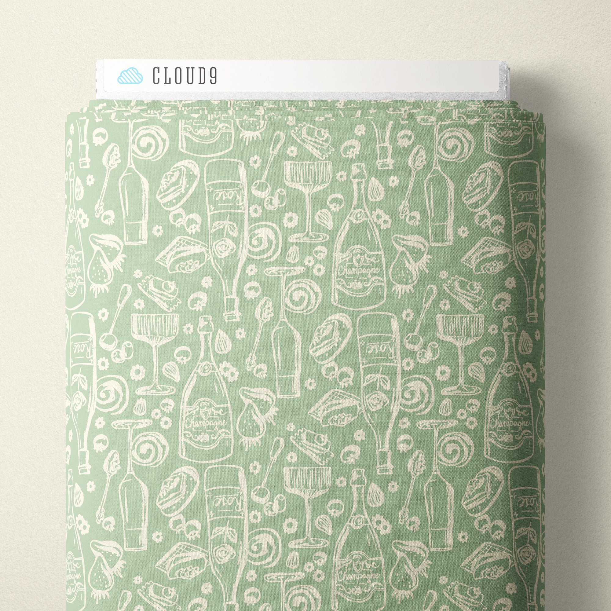 A roll of wrapping paper or fabric with a repeating white line-art pattern of bottles, glasses, and food icons on a pale mint green background, shown against a light neutral wall. A white header card at the top reads CLOUD9.