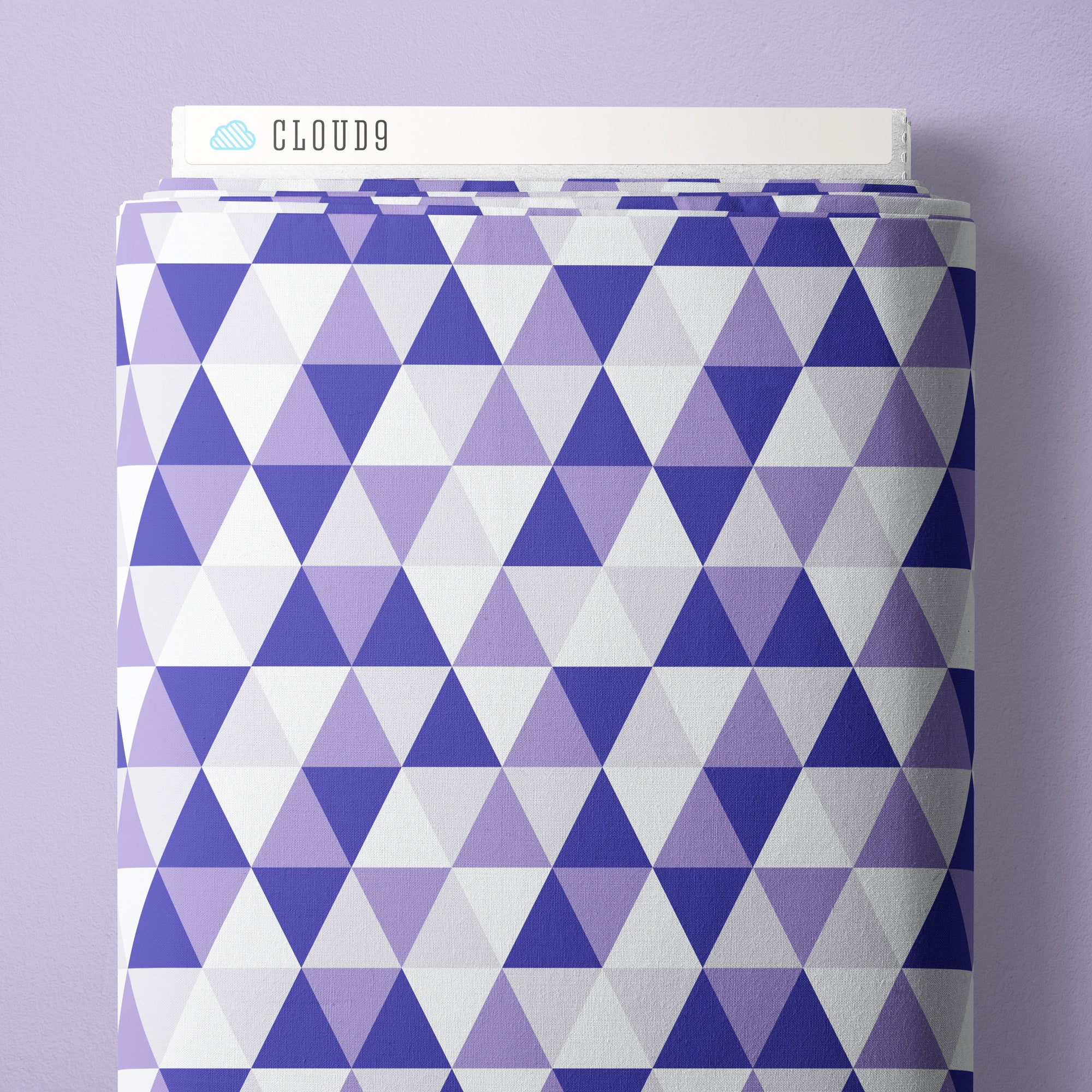 A roll of Cloud9 brand wrapping paper featuring a geometric pattern of purple, lavender, and white triangles, shown against a solid light purple background.