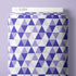 A roll of Cloud9 brand wrapping paper featuring a geometric pattern of purple, lavender, and white triangles, shown against a solid light purple background.