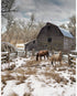 Two horses grazing in a snowy field with a wooden barn in the background.