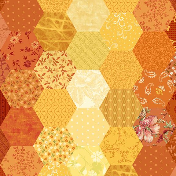 A close-up of a patchwork fabric design made of hexagonal quilt blocks in warm autumn tones, including orange, yellow, beige, and floral prints.