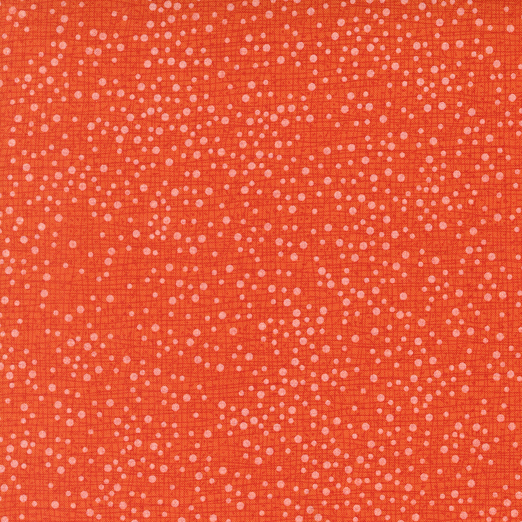 Patterned fabric with small white dots on a red-orange background