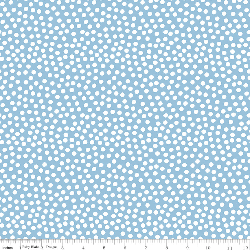 Fabric with white polka dots on a light blue background, featuring a ruler at the bottom.