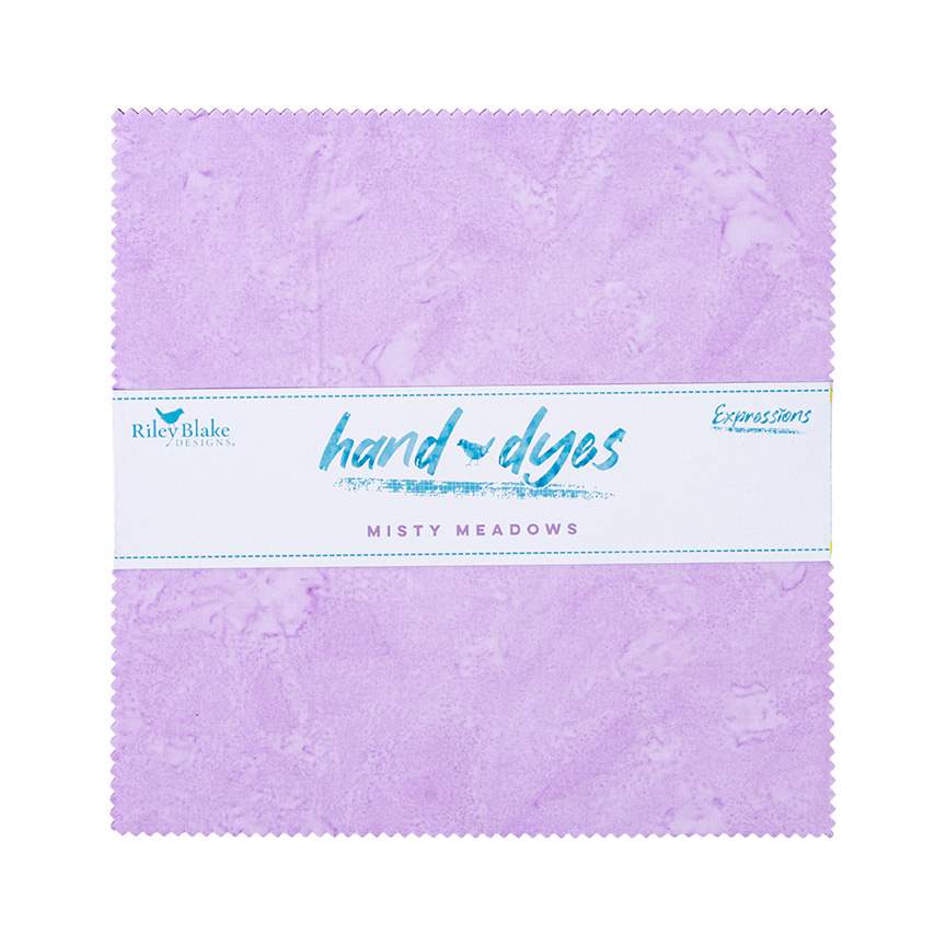 A square lavender quilt fabric block with a white paper band label across the middle. The label reads 'Riley Blake Designs', 'hand dyed', 'Misty Meadows', and 'Expressions'.