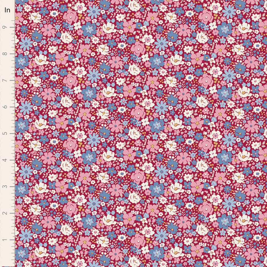 A close-up of a floral fabric pattern with small pink, blue, white, and yellow flowers on a dark red background, shown with a measurement ruler along the left edge.