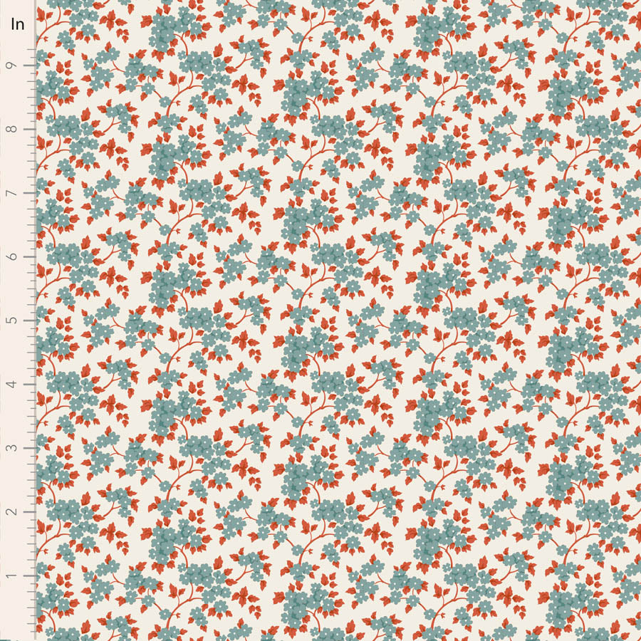 A close-up of a repeating floral pattern on fabric, showing small blue-green leaves and orange-red blossoms on a warm cream background, with a ruler along the left edge for scale.