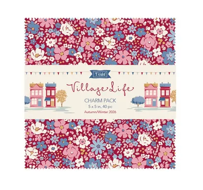 A square paper charm pack labeled 'Tilda's Village Life Charm Pack' with a floral pattern in pink, blue, and white on a burgundy background, plus small illustrated houses and trees on the center label.