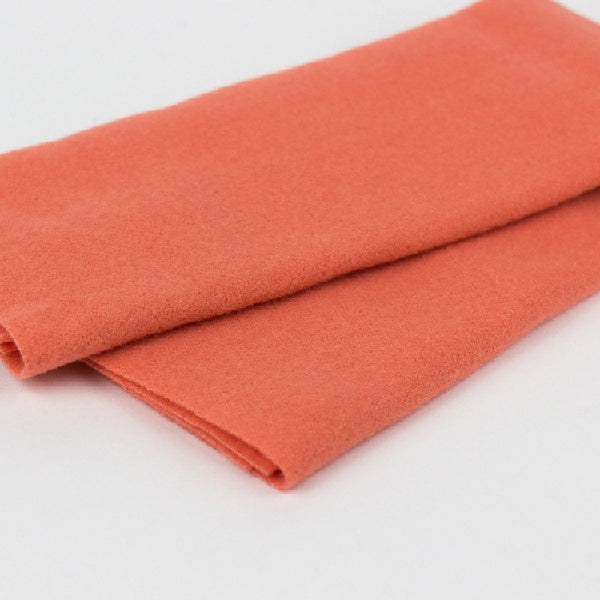 A folded piece of textured orange fabric, likely wool or felt, shown on a clean white background.