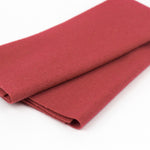 A folded piece of solid red felt fabric, showing its soft, matte texture, on a clean white background.
