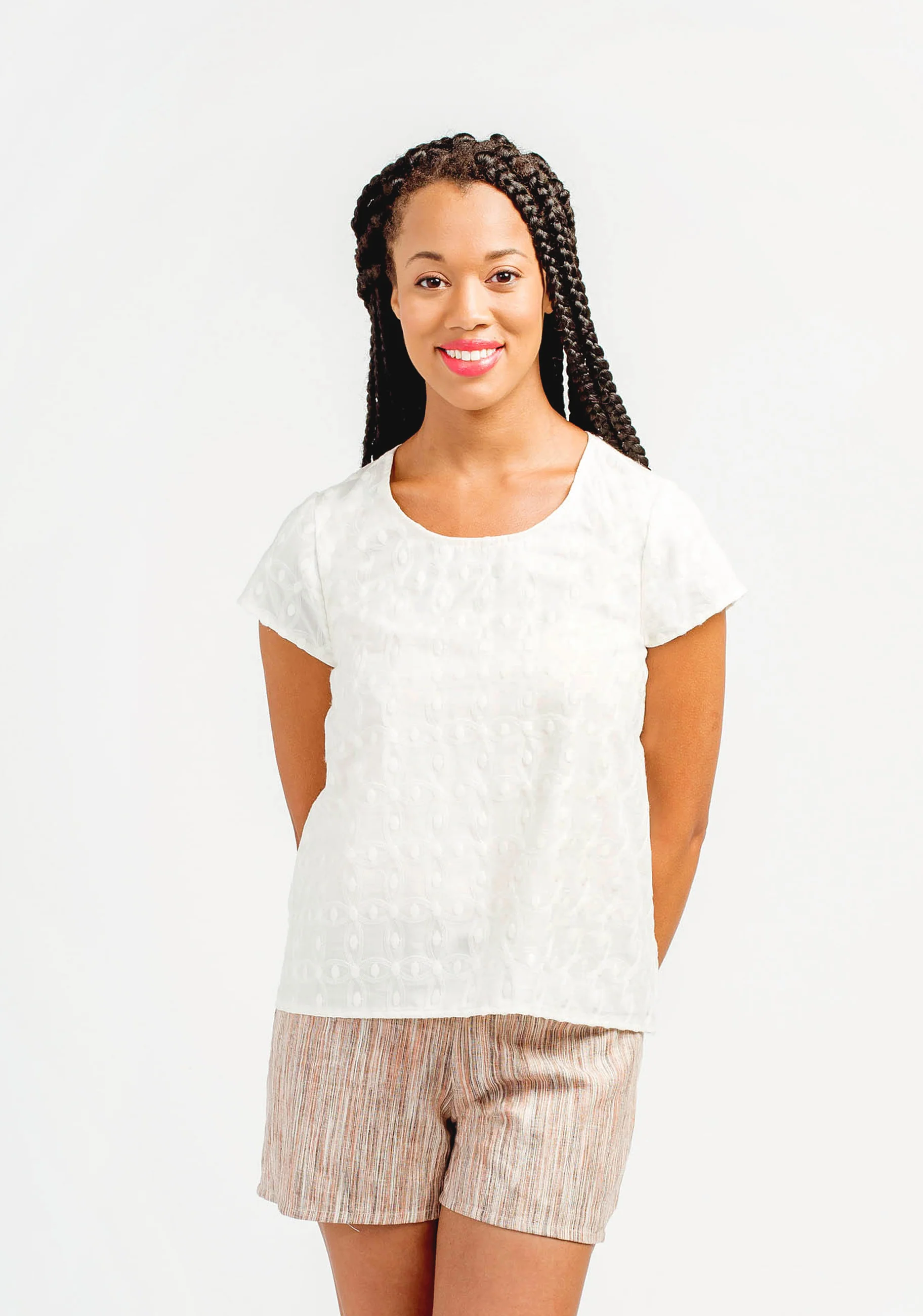 Woman wearing a white top and patterned shorts on a plain background