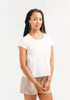 Woman wearing a white t-shirt and patterned shorts on a plain background
