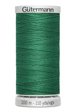 Green spool of Gutermann thread on a white background