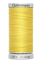 Spool of yellow thread with 'Gütermann' branding on a white background