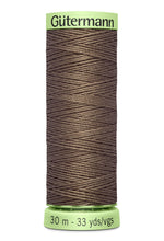 Spool of Gutermann thread with a green label on a white background