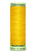 Spool of yellow thread with 'Gütermann' label on a white background