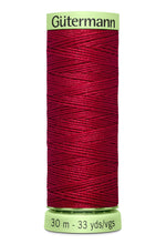 Spool of red thread with 'Gütermann' label on a white background
