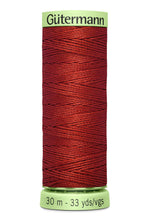 Spool of red thread with 'Gütermann' branding on a white background
